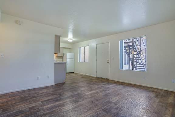 A room with wooden floors and a window showing a staircase outside.