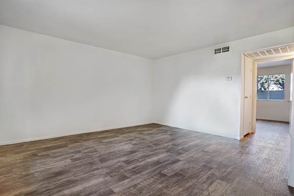 A room with a wooden floor and a door leading outside.
