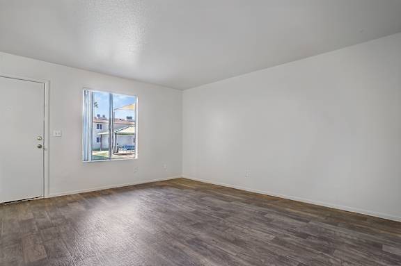 Empty room with a window and wooden flooring.