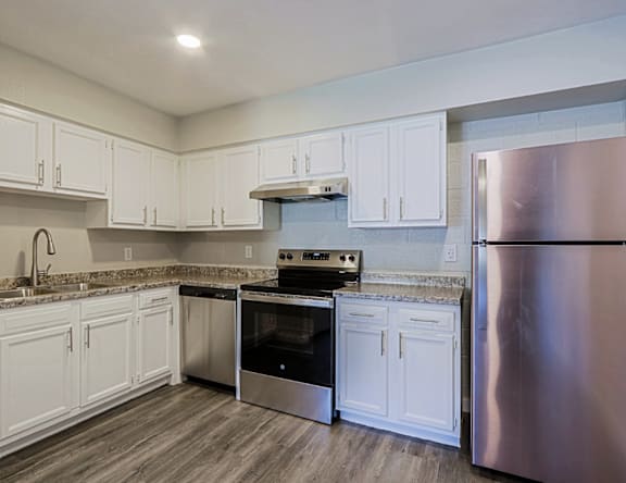 A kitchen with white cabinets and a stainless steel refrigerator.