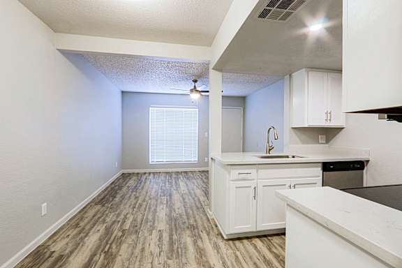 A kitchen with white cabinets and a wooden floor.