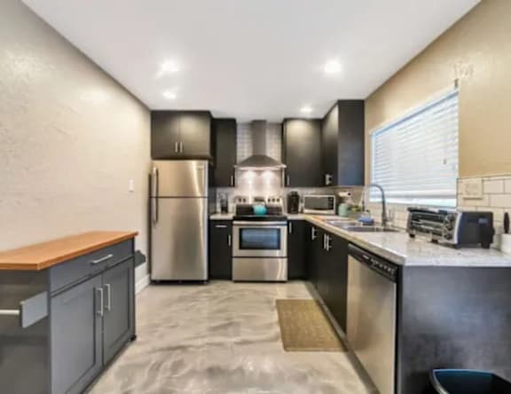 A modern kitchen with stainless steel appliances and a wooden countertop.
