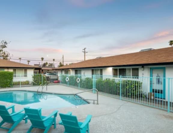 A pool area with blue chairs and a building in the background.