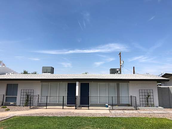 A white house with a black fence and a blue sky.
