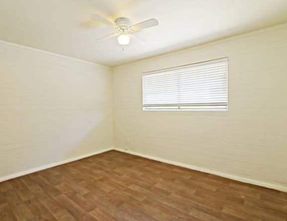 A room with a ceiling fan and a window with blinds.
