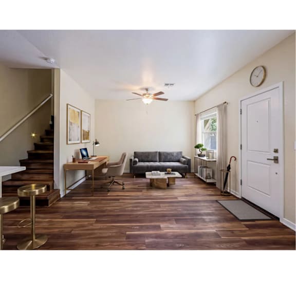 A living room with a couch, a chair, a coffee table, and a staircase.