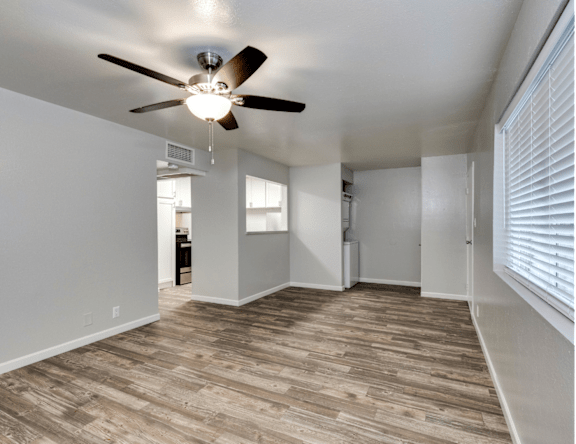 A room with a ceiling fan and wooden flooring.