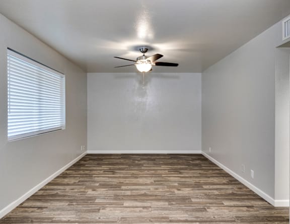 A room with a ceiling fan and wooden flooring.