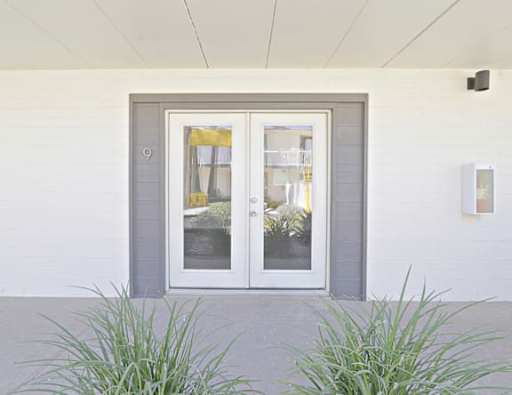 A grey door with a glass window and a number 9 on the wall.