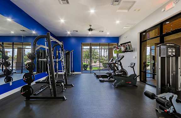 A gym with a variety of equipment including treadmills, weights, and exercise machines.
