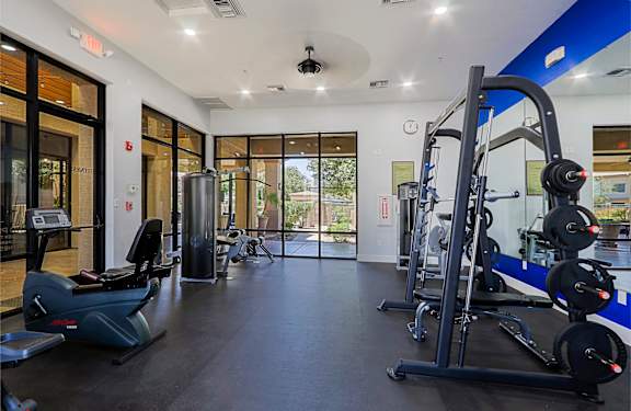 A gym with a variety of equipment including treadmills, elliptical machines, and weight machines.