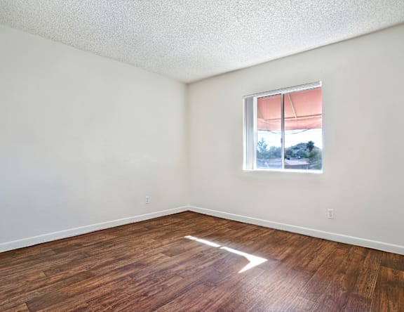 A room with a window and wooden flooring.