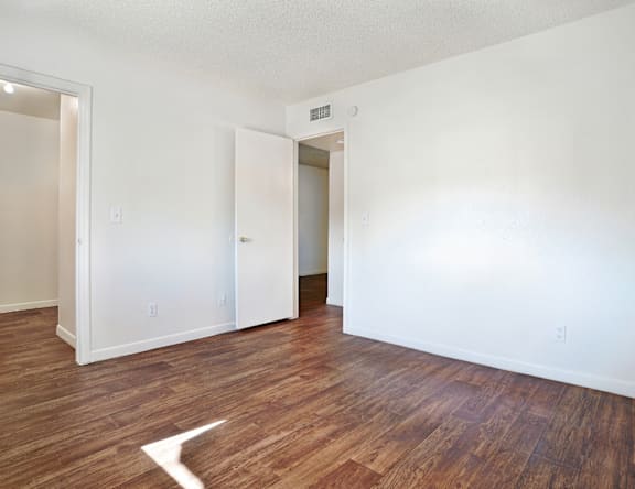 A room with wood flooring and two doors.