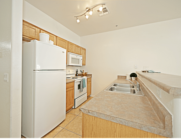 A kitchen with a white refrigerator, white oven, and white microwave.