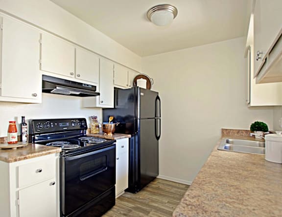 A kitchen with black appliances and white cabinets.
