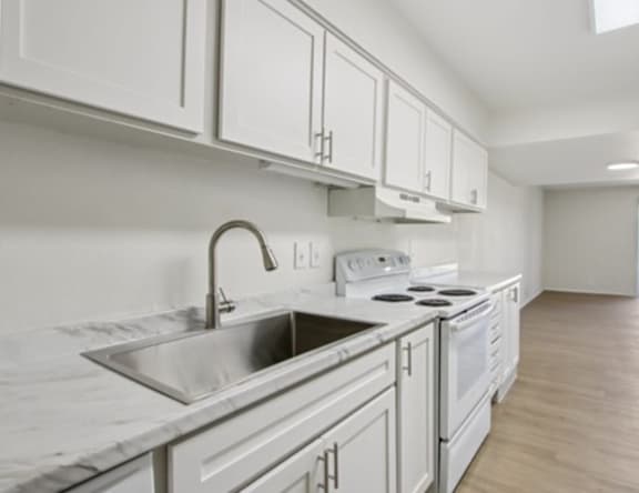 A modern kitchen with white cabinets and stainless steel appliances.