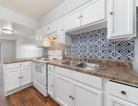 A kitchen with white cabinets and a patterned backsplash.