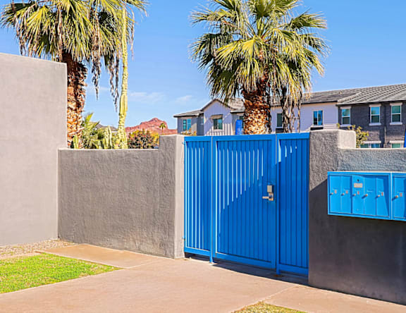 A blue gate is in front of a grey wall.