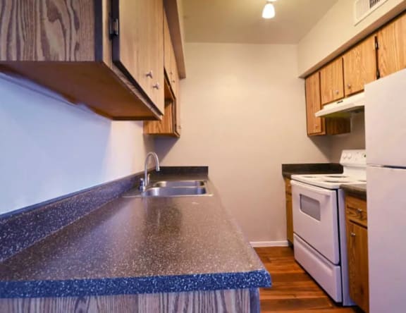 A kitchen with a white refrigerator and wooden cabinets.