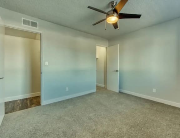 A room with a ceiling fan and carpeted floor.