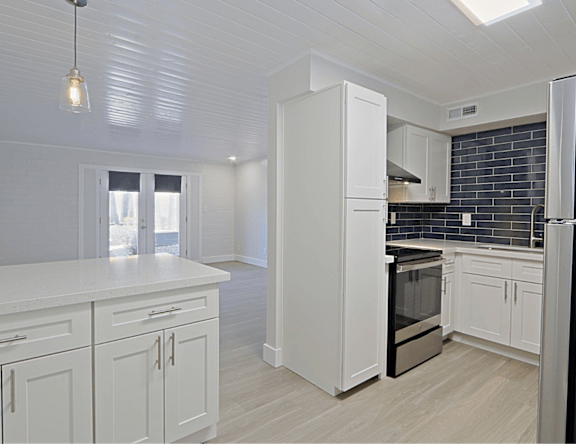 A kitchen with white cabinets and a black backsplash.