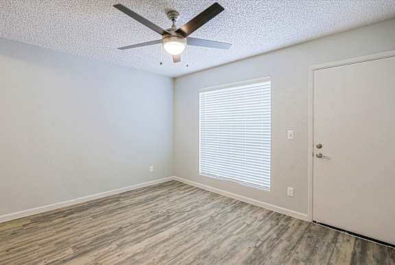 A room with a ceiling fan and a door.