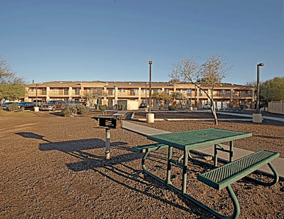 Picnic tables and benches are set up in a dirt field.