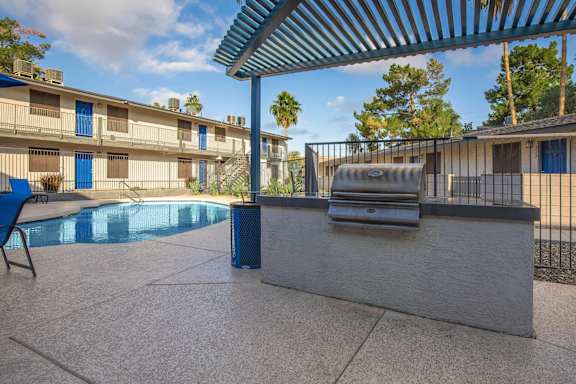 A pool area with a grill and a chair.