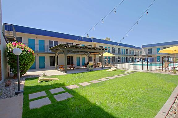 A sunny day at the poolside with a building in the background.