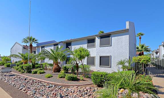 A modern house with a grey exterior and a landscaped garden in front.