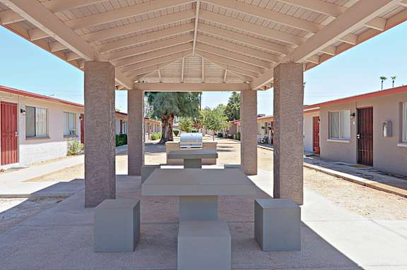 A white pavilion with a table and chairs in the middle.