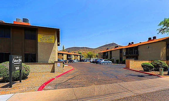 A street view of a residential area with apartment buildings and a sign that reads "Edison Village".