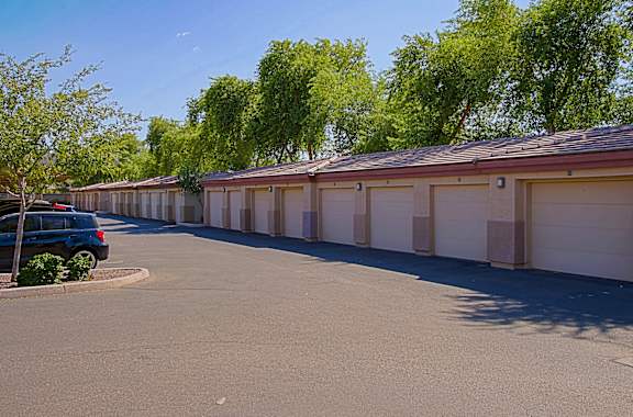 A row of garages with a car parked in front of the first one.