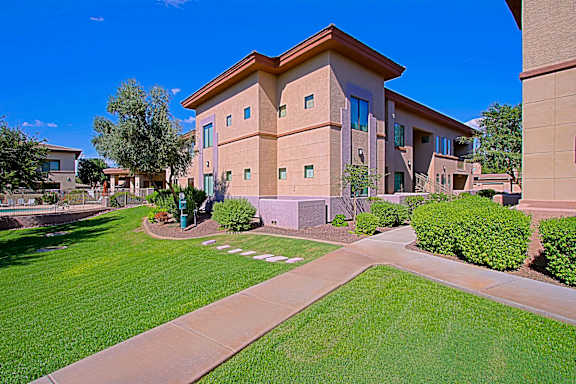A building with a brown roof and tan walls with a green lawn in front.