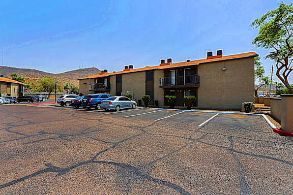 A parking lot in front of a building with cars parked.