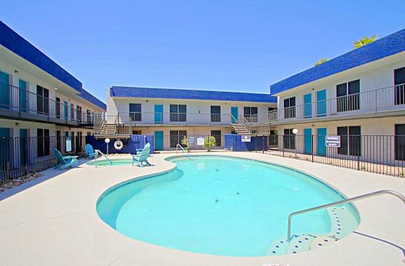 A swimming pool in front of a building with blue trim.