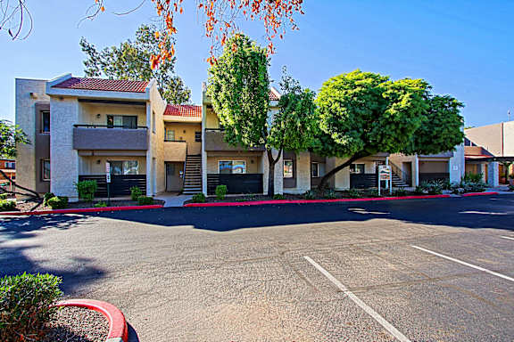 A parking lot in front of a building with trees.