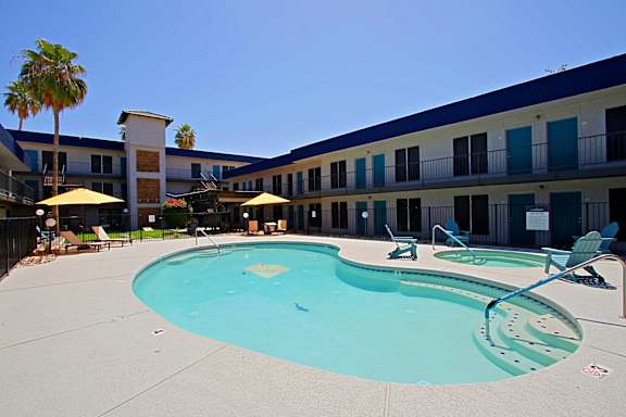 A large swimming pool in front of a building with a blue sky in the background.