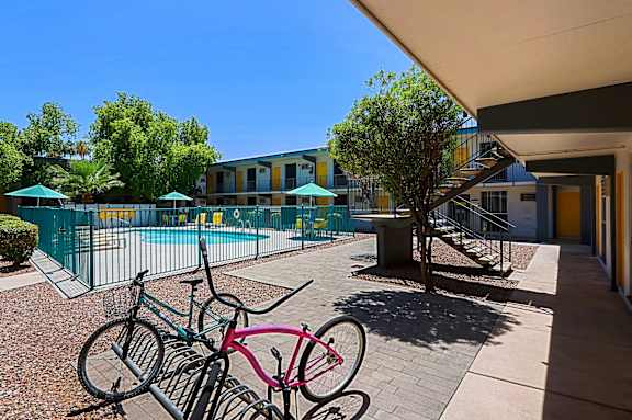 A bicycle is leaning against a rack on a brick patio.