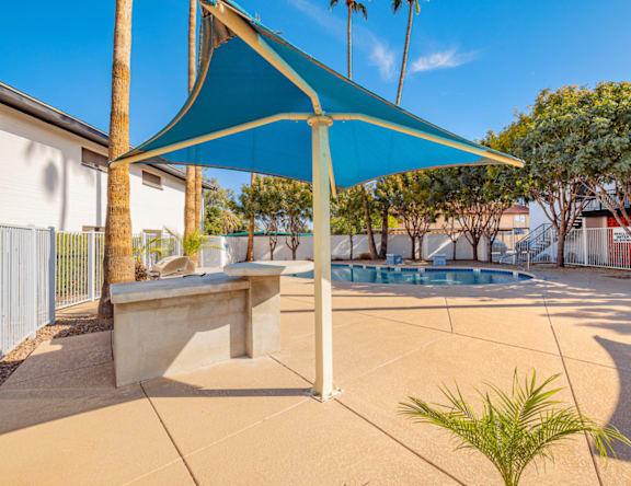 A blue shade structure is over a concrete bench.