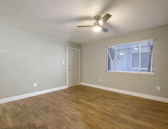 A room with a ceiling fan and a window with blinds.