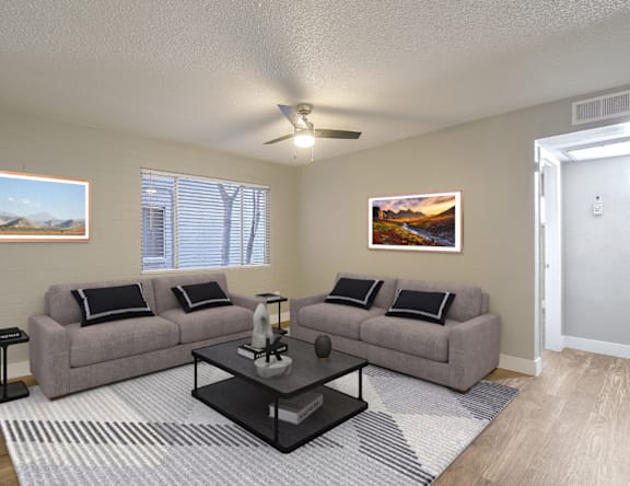 A living room with a grey couch, a coffee table, and a painting on the wall.