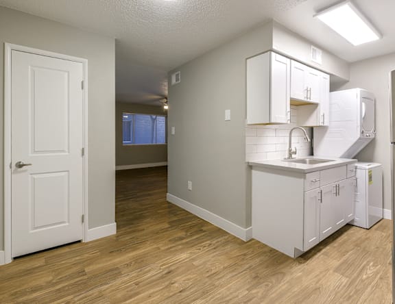 A kitchen with white cabinets and a wooden floor.