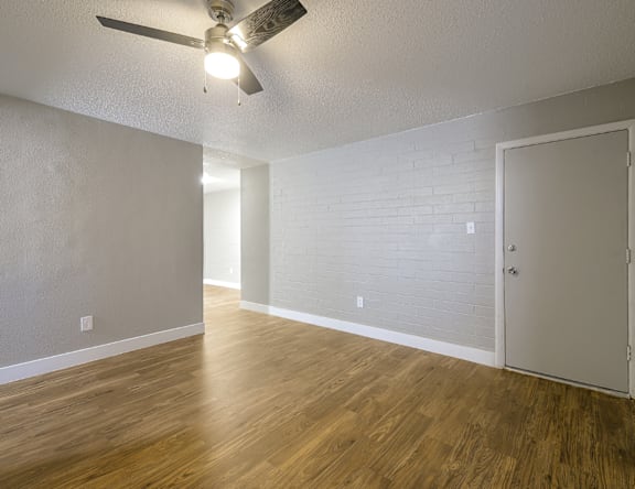 A room with a ceiling fan and wooden flooring.