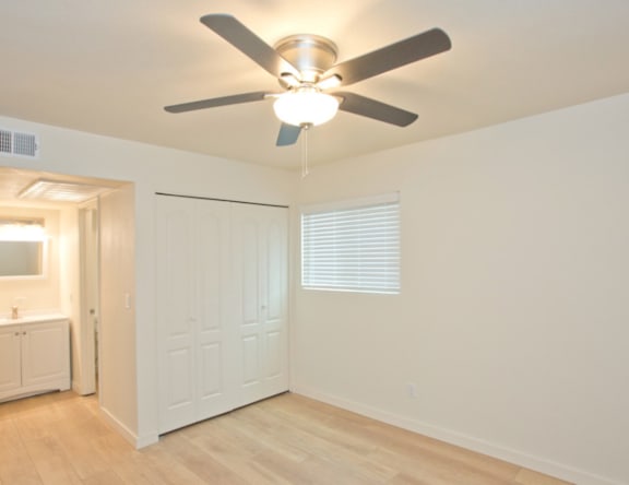 A room with a ceiling fan and a white door.