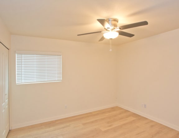 A room with a ceiling fan and a window with blinds.
