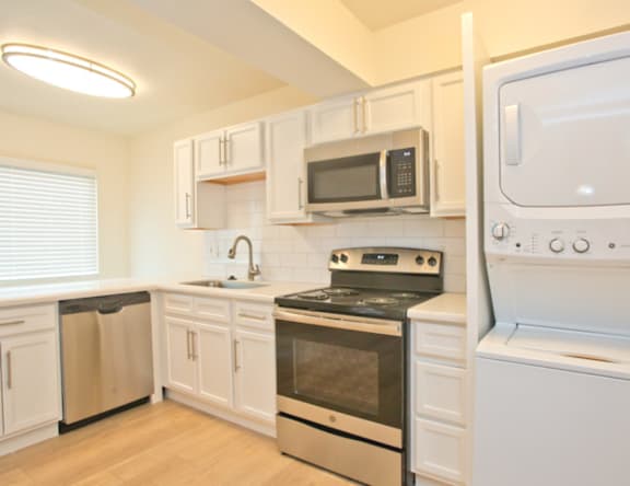 A kitchen with white cabinets and appliances.