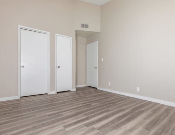 Three white doors are in a room with wood flooring.