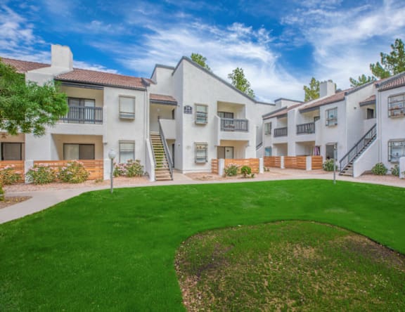 A row of white apartment buildings with green lawns in front.