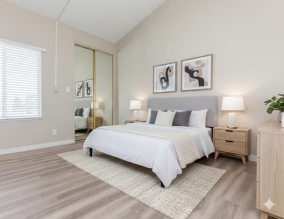 A bedroom with a large bed, two nightstands, and a plant.